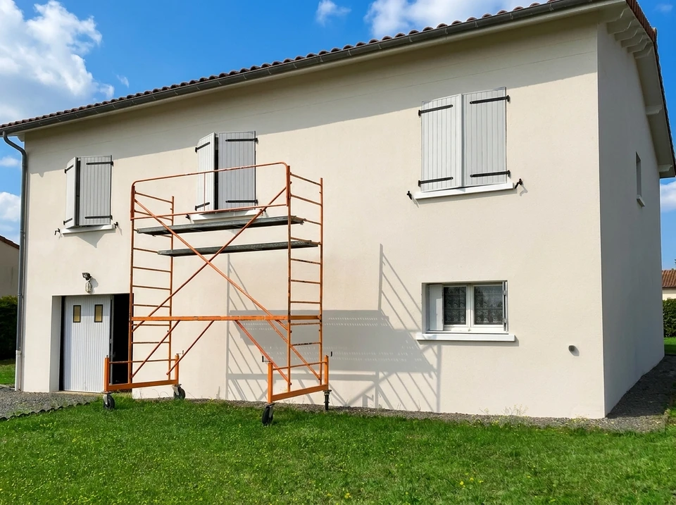 Peintre professionnel en combinaison bleue et casquette blanche applique de la peinture blanche au rouleau sur un mur intérieur