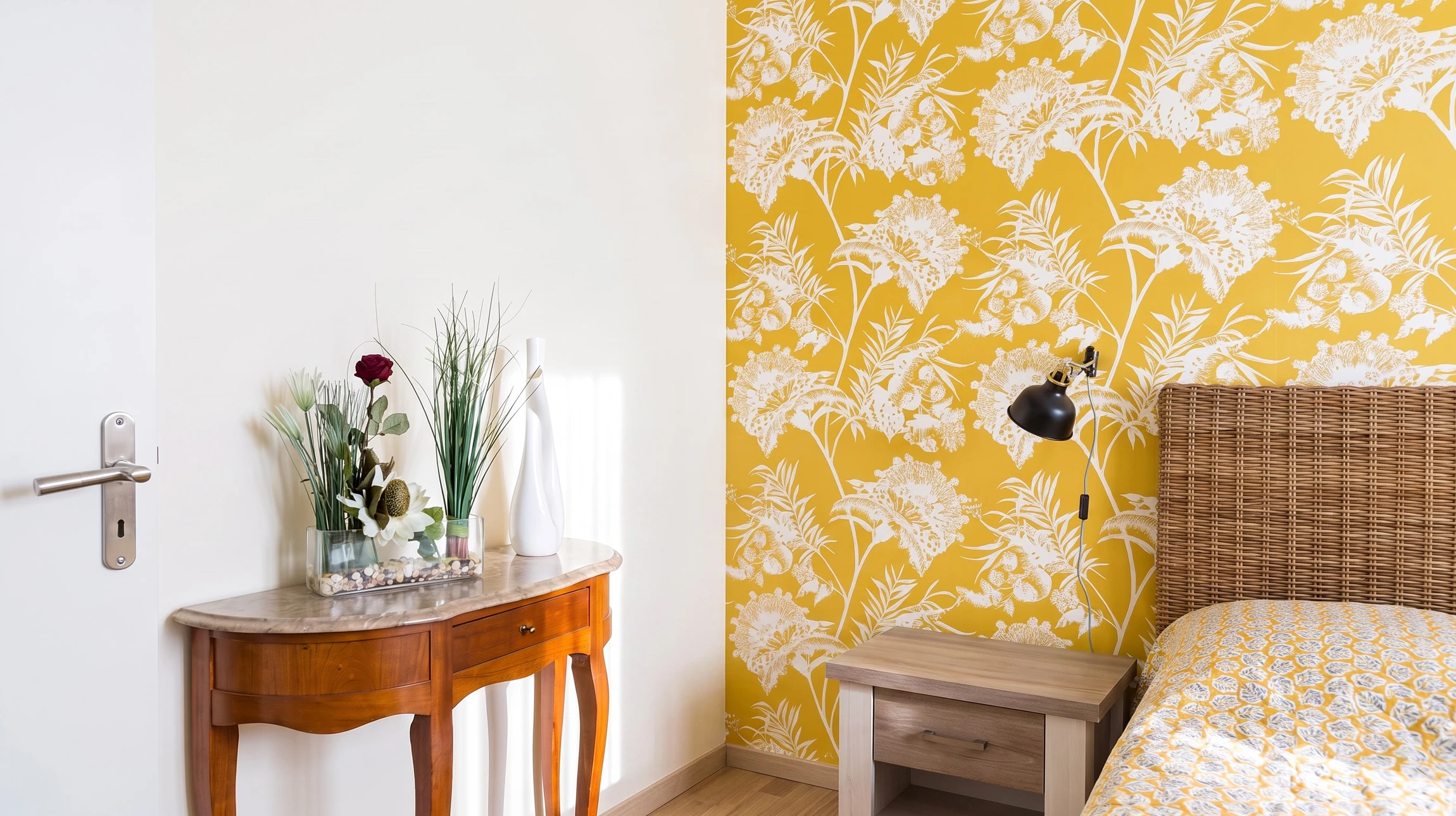 Photographie d'un intérieur rénové montrant un mur avec papier peint récemment posé, présentant un motif élégant et discret. Un artisan en tenue professionnelle effectue les derniers ajustements près du mur. L'éclairage met en évidence la qualité de la pose et la finition impeccable du papier peint. L'atmosphère générale doit être celle d'une rénovation soignée et professionnelle dans un cadre domestique de qualité.