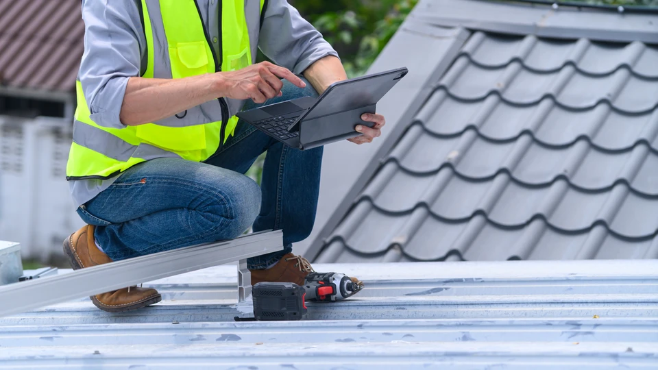 Photographie d'un artisan plâtrier ou peintre dans un intérieur résidentiel en cours de rénovation, en train de discuter avec un client sur le chantier. L'artisan tient un document (devis, plan ou cahier de suivi) et tous deux examinent un mur ou une surface en cours de travaux. La scène doit illustrer la relation de confiance, le dialogue et le suivi personnalisé entre le professionnel et le client, dans un contexte d'intérieur à rénover (chambre, salon ou cuisine visible en arrière-plan). L'accent doit être mis sur l'interaction professionnelle et l'implication personnelle du dirigeant auprès du client.