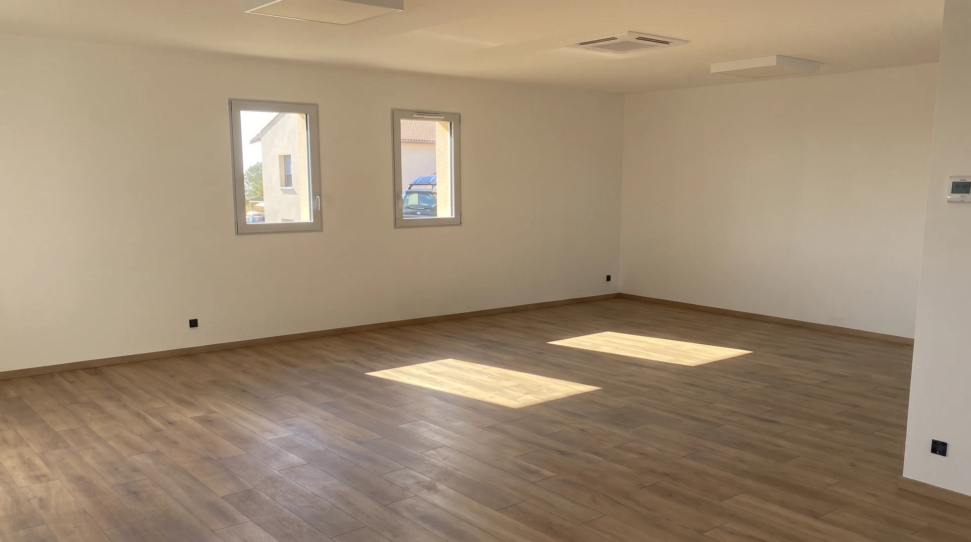 Intérieur résidentiel lumineux montrant un sol PVC ou souple de qualité professionnelle, avec un rendu réaliste de motifs ou de textures (imitation pierre, béton ou design contemporain), posé dans un espace moderne transformé. Le sol doit occuper une place visuelle importante et mettre en évidence la transformation apportée par le revêtement souple dans cet espace rénové.
