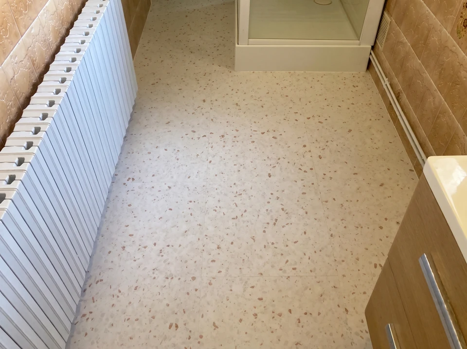 Ouvrier appliquant un revêtement de sol liquide autonivelant dans un intérieur résidentiel