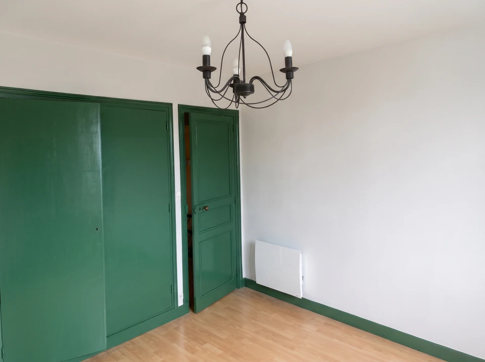 Scène d'intérieur montrant une personne appliquant une finition sur une surface en bois à l'aide d'un rouleau de peinture